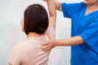 © M+Isolation+Photo - Young Asian nurse assisting middle-aged female patient on a couch doing physical therapy, focusing on muscle strengthening, rehabilitation, stretching,shoulder pain management in healthcare facility