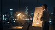 © Aksaka - Man drawing strategy on flipchart at night in office