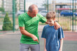 © Ольга Апанасенко - Father teaches his son how to play basketball. The boy throws the ball into the hoop at the playground. Generation. Sports. Hobbies