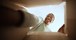 © FantiFlash/peopleimages.com - Black woman, open box and happy with POV in home, low angle or ecommerce for product, order or delivery. Person, excited and smile with cardboard package, parcel and online shopping at apartment