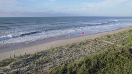 Wall Mural - drone shot of ocean swells coming in from a hurricane offshore, aerial shot with red flag