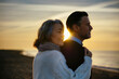© Westend61 - Smiling mature woman and man enjoying sunrise at beach
