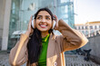 © Westend61 - Thoughtful young woman wearing headphones outside building