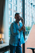 © Tj - Mature businessman standing by the hotel room window, talking on his smartphone while enjoying a stunning view of the urban skyline and bustling city below