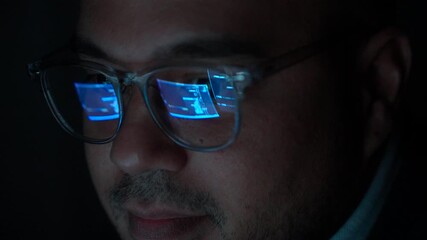 Close-up Reflection green code in lenses of glasses and eye of Male programmer works late at night, focusing on software development, coding, and cybersecurity analysis in dark room.