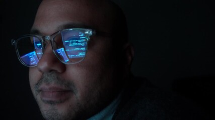 Close-up Reflection green code in lenses of glasses and eye of Male programmer works late at night, focusing on software development, coding, and cybersecurity analysis in dark room.