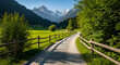 © Hafizha - Idyllic alpine landscape featuring a winding path through vibrant green meadows, framed by a rustic wooden fence, leading towards majestic snow-capped mountains under a clear blue sky, embodying