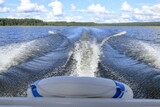 A tail wake on the water behind a motor boat on a lake. 