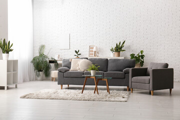 Poster - sofa, tables and houseplants near white brick wall in interior of living room