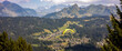 Flying paraglider passing by in stunning French Alps scenery with Mont Blanc massive in the background and Les Gets town in valley below. Anamorphic cinematic panorama.