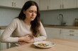© LK  - Woman holding her stomach, suffering from pain after eating. Concept of food poisoning, indigestion, digestive problems, health issues, and wellness at home kitchen.