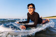 © Kyryl Gorlov - Smiling woman enjoys surfing on Baltic Sea waves, lying on board with splashing water around. Bright sunlight and her laughter reflect pure joy, freedom and vibrant summer adventure