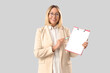 © Pixel-Shot - Mature female math teacher with clipboard and pen on grey background