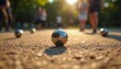 © Viktor - Close-up of petanque ball on gravel court during sunny day game. Friends enjoy leisure competition, playing bocce ball in social summer recreation activity. Focus on metallic sphere, challenging
