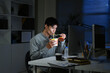 © Stella 16 - Asian young businessman eating noodles while working in office at night.