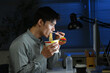 © Stella 16 - Asian young businessman eating noodles while working in office at night.