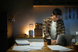© Stella 16 - Focused man working late at night on laptop in kitchen with coffee