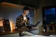 © Stella 16 - Young man sits in the kitchen at the bar counter works in laptop and drinks a coffee. Home atmosphere, work in the evening after a hard day. Home office.