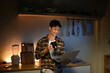 © Stella 16 - Young man sits in the kitchen at the bar counter works in laptop and drinks a coffee. Home atmosphere, work in the evening after a hard day. Home office.