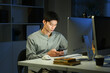© Stella 16 - Shot of a young businessman using a laptop and smartphone during a late night in a modern office