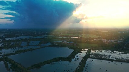 Wall Mural - Cinematic 4K aerial of dramatic storm clouds and golden sun rays illuminating wetlands and farmlands—perfect for documentaries, nature, and inspirational projects.