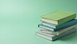 © Maryna - Stack of four hardcover books in pastel colors green blue, grey on solid mint green background. Book covers smooth, matte. Books slightly tilted on side. Clean minimalist composition suitable for