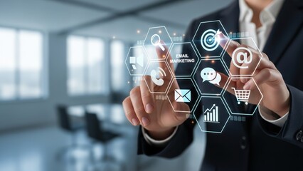 Man in gray suit standing in bright office using floating holographic display with marketing icons email analytics and marketing automation digital concept