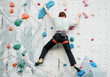 © Flowal93 - a woman is rock climbing on a colorful artificial wall.