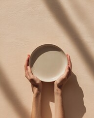 Wall Mural - Minimalist composition with hands holding ceramic plate on neutral background for modern design