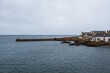 © Travel 'n' Lifestyle - View of a calm, dark sea meeting a rocky coastline topped with quaint white houses under a cloudy sky, Findochty, Scotland, United Kingdom.