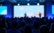 © yang - Large crowd gathered in front of a conference stage with speakers, set against a blurred blue background, capturing the event atmosphere. High quality