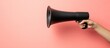 © yasna - A hand holding a black megaphone on a coral-colored background, ready to announce.