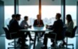 © wang - Group of businesspeople negotiating gathered in modern conference room, blurred silhouettes view, meeting behind closed glass doors. Business communication, workflow, decision-making, strategy sharing