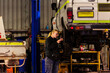 © Austockphoto - Female mechanic working on mining fleet vehicles in industrial workshop with cars on lift
