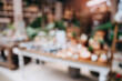 © JK_kyoto - Blurred Background of a Flower Shop with Beautiful Floral Arrangements and Decorative Items Displayed on Tables