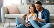 © Prostock-studio - Online Shopping Concept. Cheerful Mixed Couple Using Laptop And Credit Card At Home, Happy Interracial Lovers Enjoying Purchasing Things In Internet, Relaxing On Floor In Living Room Together