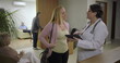 © Marco - Female doctor reviewing medical details on tablet with woman in reception area of clinic, positive healthcare conversation near waiting area