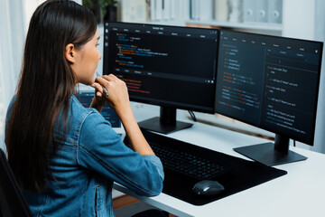 Young Asian IT developer looking online information on pc for beautiful pose with coding program data of website application, wearing jeans shirt. surround by safety analysis two screens. Stratagem.