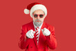 © Studio Romantic - Isolated shot of self confident Santa Claus in stylish clothing and hat, looking through sunglasses and pointing directly at you, isolated over vivid red background. Hey you, Happy New Year