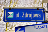 Ustroń Zawodzie - słynne piramidy. Niebieski znak drogowy wskazujący ulicę Zdrojową z herbem regionu, położony na Śląsku.
