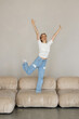 © F8  \ Suport Ukraine - Young pretty woman jumping on the sofa at home.