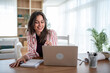 © Migma_Agency - Smiling woman working from home using laptop and taking notes