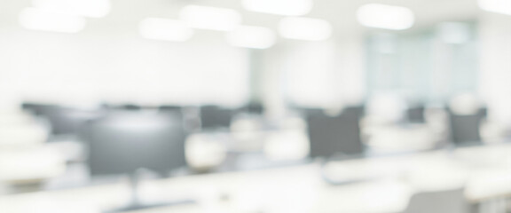 Blurred office interior with desks and chairs in a bright white space, reflecting a classroom-style professional environment with organized layout and clear modern design.