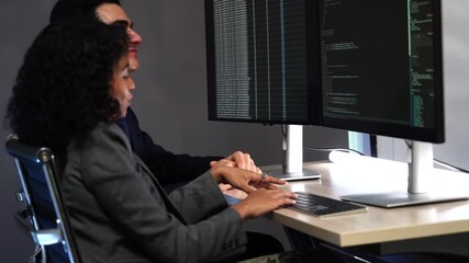 Asian female finance officer wearing glasses with a co-worker programmer discussing software writing. A coder or developer working in a computer display discussing problem solving.