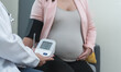 © Pruksachat - Gynecologist doctor using blood pressure monitor evaluates patient and records results of medical checkup health and advise woman in 25 weeks of pregnancy. Unrecognized people. Copy space