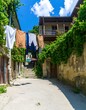 © Heran - Sunny alleyway with clothes strung between weathered stone buildings and a stairway.