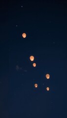 Wall Mural - Minimalist pastel lanterns glowing faintly in quiet night sky floating softly upward toward glowing muted stars