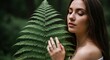 © Tetiana - Young caucasian female with long brown hair holding fern in nature