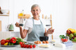 © New Africa - Senior woman cooking at white marble table in kitchen
