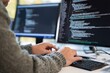 © oksa_studio - Computer programmer writing code on a desktop computer keyboard in an office, developing software